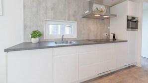 A modern kitchen with a large island, stainless steel appliances, and a window above the sink.