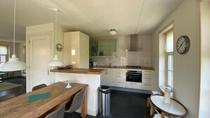Una cocina compacta con una mesa de comedor de madera, una pequeña isla y un cesto de basura.