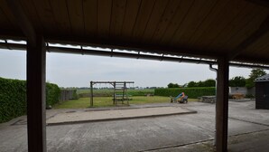 Un espace extérieur abrité, doté d’un sol en béton, d’une balançoire et d’une table de pique-nique.