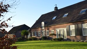 Une maison à deux étages, construite en briques, avec un toit en pente, de grandes fenêtres et une pelouse bien entretenue.