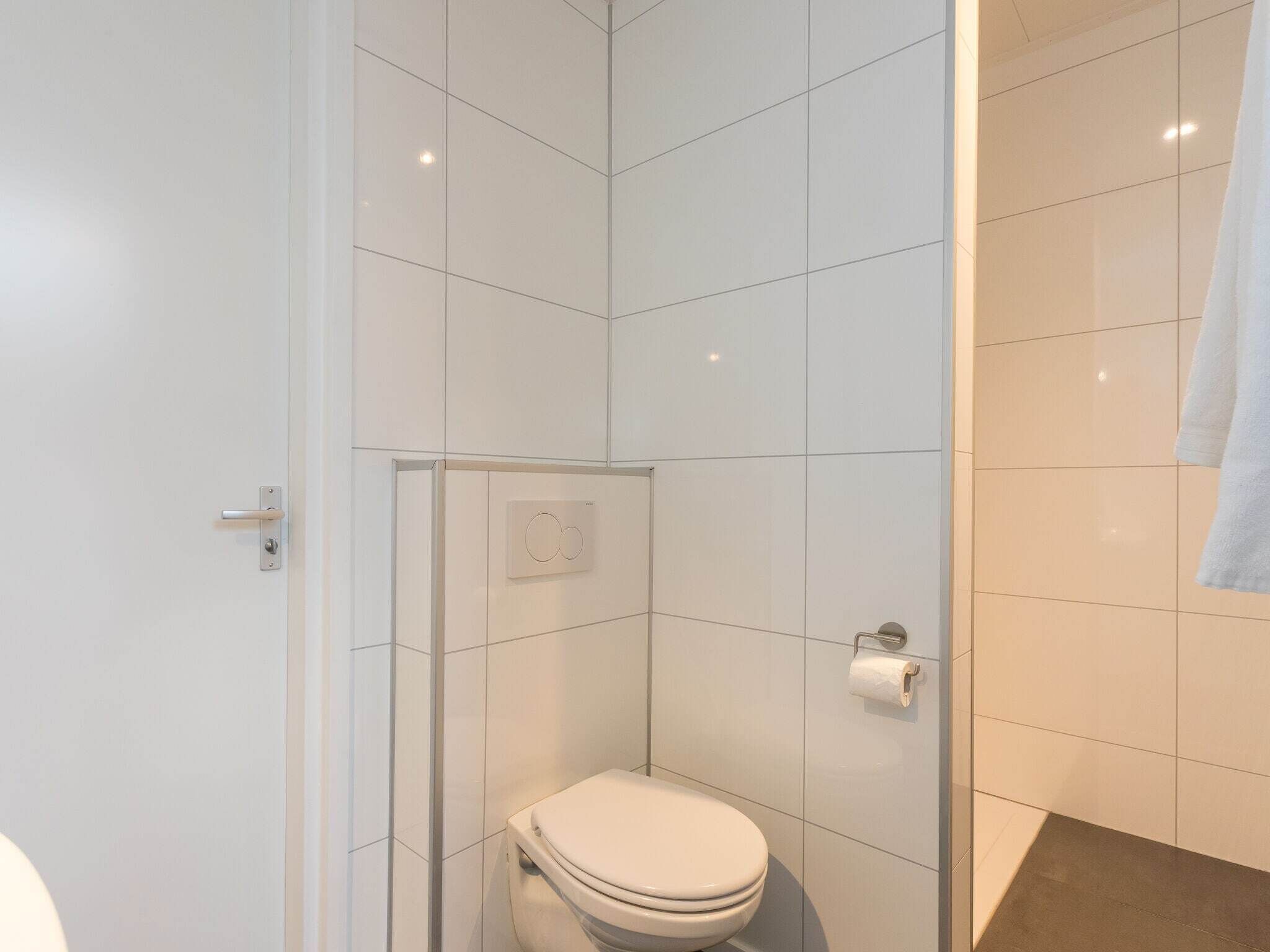 Une salle de bain moderne avec une douche à parois de verre, des toilettes et un porte-serviettes.