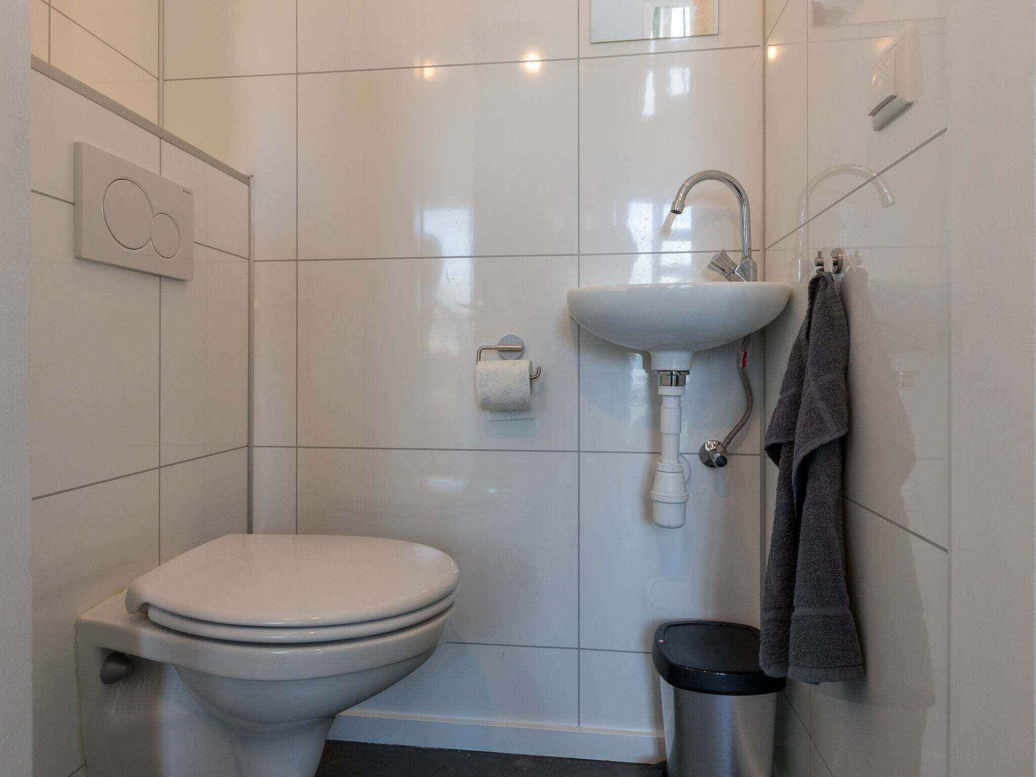 Un baño moderno con inodoro blanco, lavamanos y ducha.