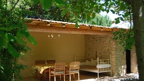 Una habitación con una cama, una mesa con sillas y una pared de piedra.