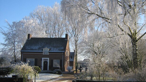 A two-story brick house with a sloped roof, a front door, and a visible chimney. - Holiday Home in Soerendonk With Garden (Soerendonk)