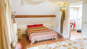 A bedroom with a bed, a wooden headboard, a bedside table, a basket, and a window with curtains. - Holiday Home in Soerendonk With Garden (Soerendonk)