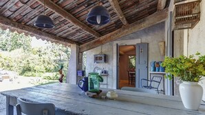 A rustic outdoor seating area with a wooden table, metal chairs, hanging lamps, and a potted plant. - Cottage in Oppede With Pool and Garden (Oppede)