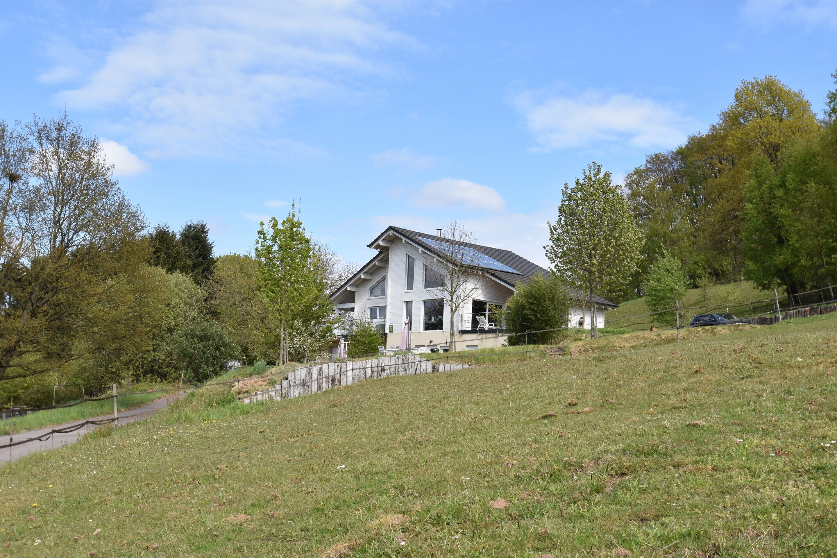 A modern house with a sloped roof, a visible solar panel, and a small shed.
