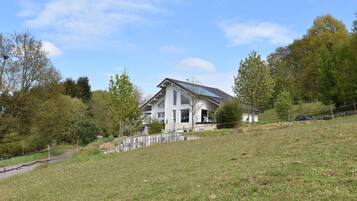 A modern house with a sloped roof, a visible solar panel, and a small shed.