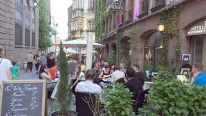 An outdoor café with tables and chairs, surrounded by greenery and buildings. - Wheelchair-friendly Escape (Varsberg)