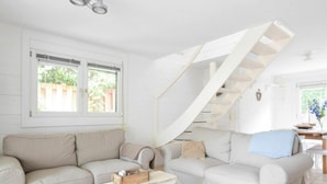 A spacious living room with a beige sofa, a small white coffee table, and a staircase leading to another level. - Spacious Holiday Home in Oostkapelle (Oostkapelle)