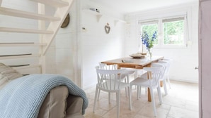 A bright, open-plan living and dining area with a staircase, white walls, and a large window. - Spacious Holiday Home in Oostkapelle (Oostkapelle)