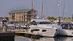 A marina with several yachts docked, a building with a sloped roof, and a clear sky. - Holiday Home in Kamperland (Kamperland)