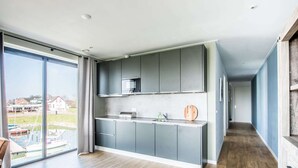 A modern kitchen with grey cabinets, a wooden countertop, and a view of a marina through large windows. - Holiday Home in Kamperland (Kamperland)