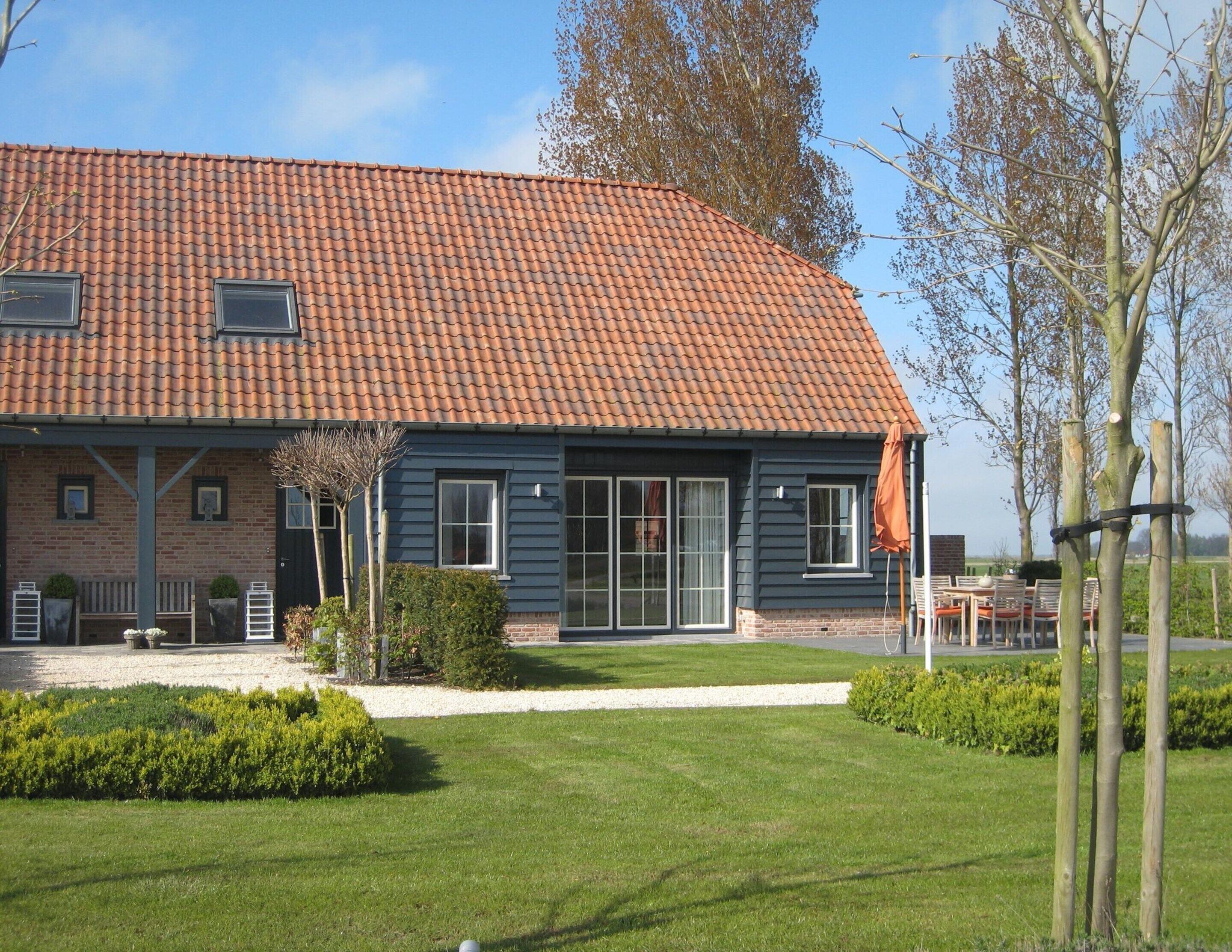 A two-story house with a red-tiled roof, brick walls, and large windows.
