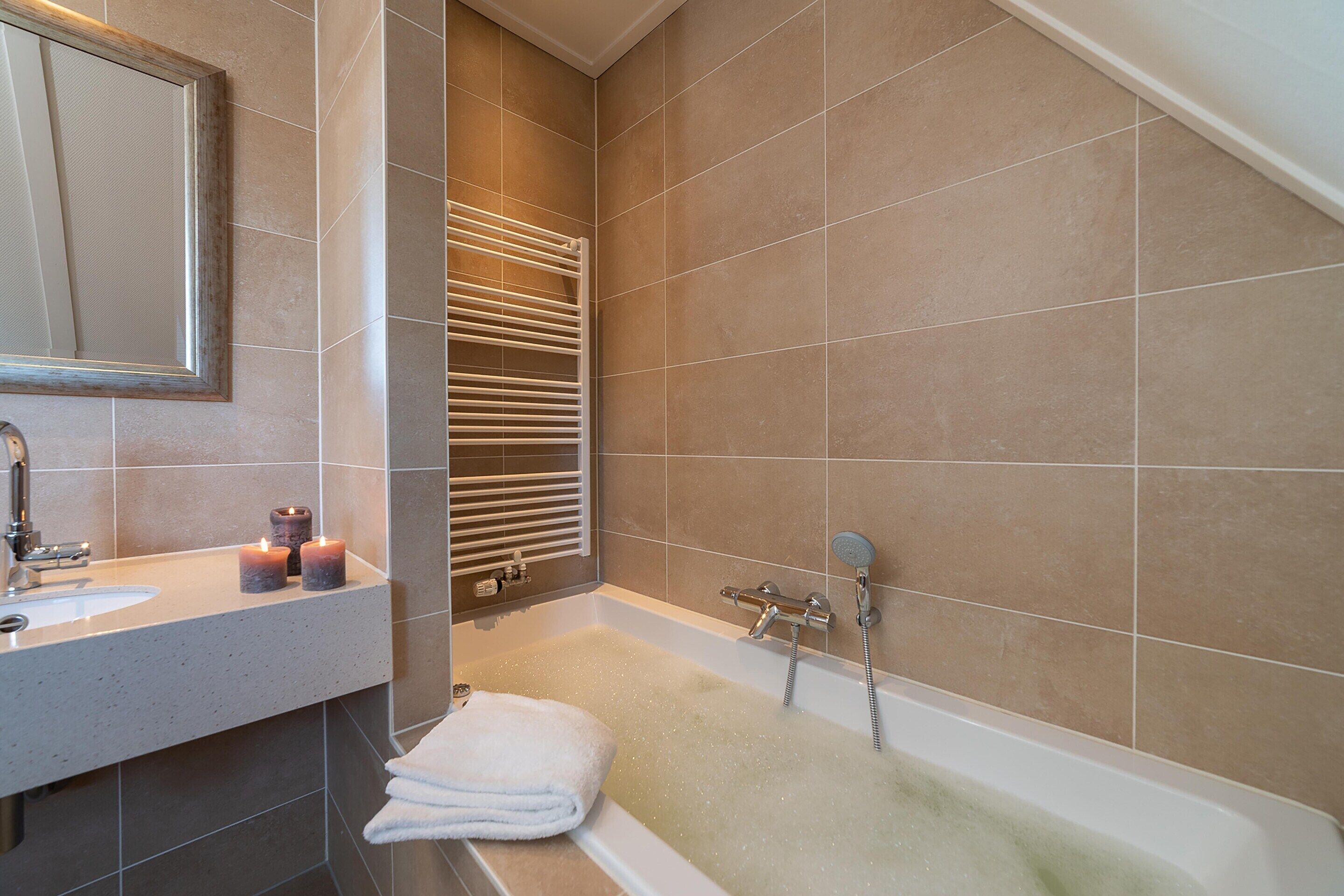 Un baño con bañera, lavamanos y espejo.