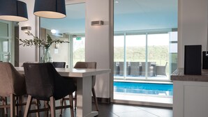 Ein moderner Essbereich mit Blick auf den Pool, ausgestattet mit einem Tisch, Stühlen und einer Pflanzvase.