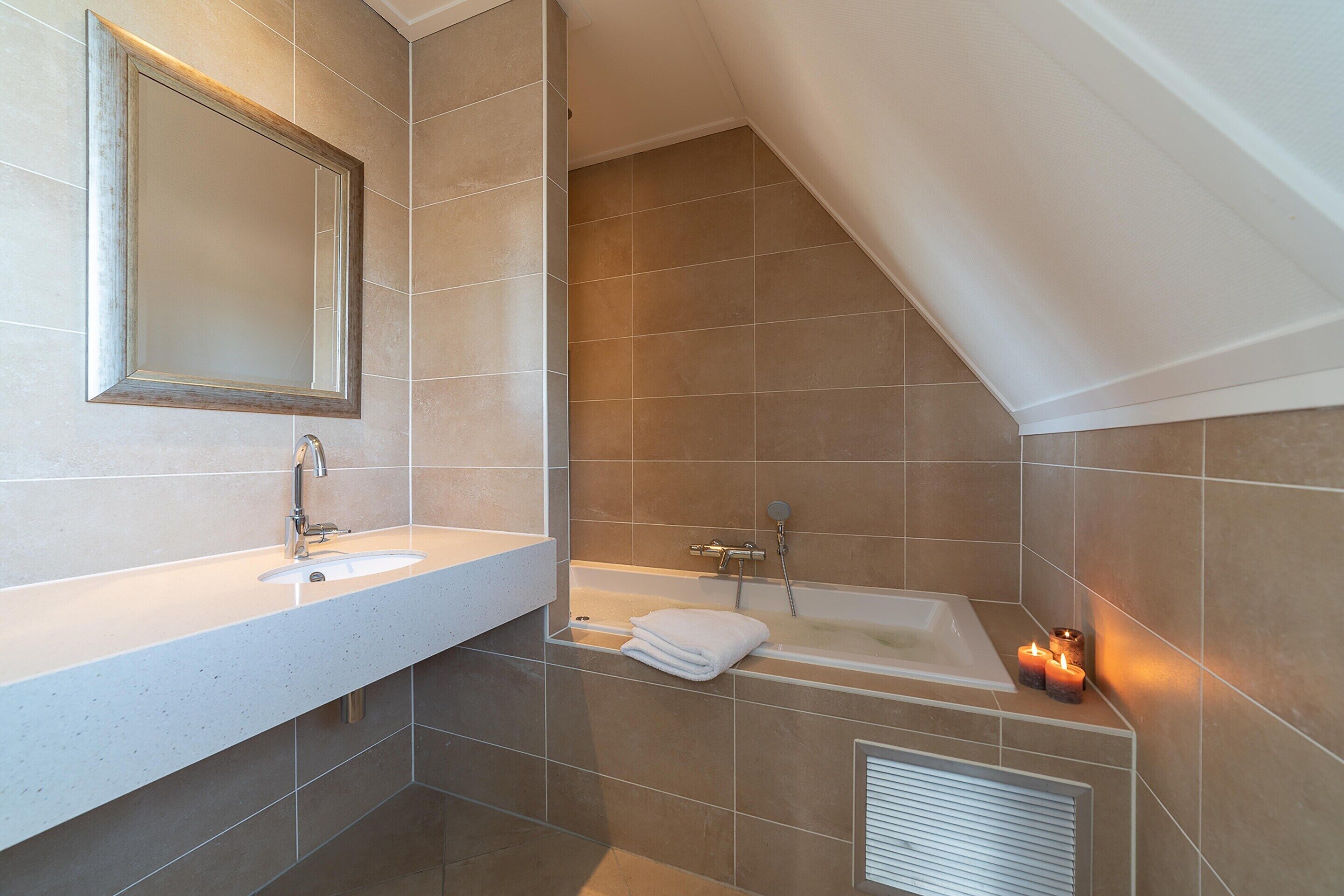 A modern bathroom with a sink, mirror, and bathtub.
