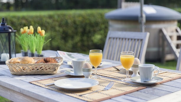 A breakfast table set outdoors with a basket of bread, eggs, and juice glasses. - Cozy House near River (Notter)