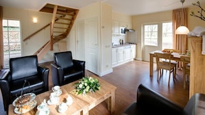 A spacious living room with a wooden staircase, a dining area with a wooden table set for a meal, and a kitchen in the background. - Cozy House near River (Notter)