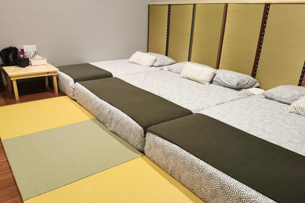 Een kamer met een bed, nachtkastje en een kleine tafel met een koffiezetapparaat.