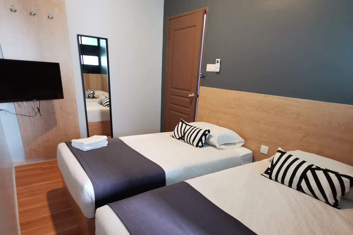 Een hotelkamer met twee bedden, een houten hoofdbord, een flatscreen televisie en een spiegel.