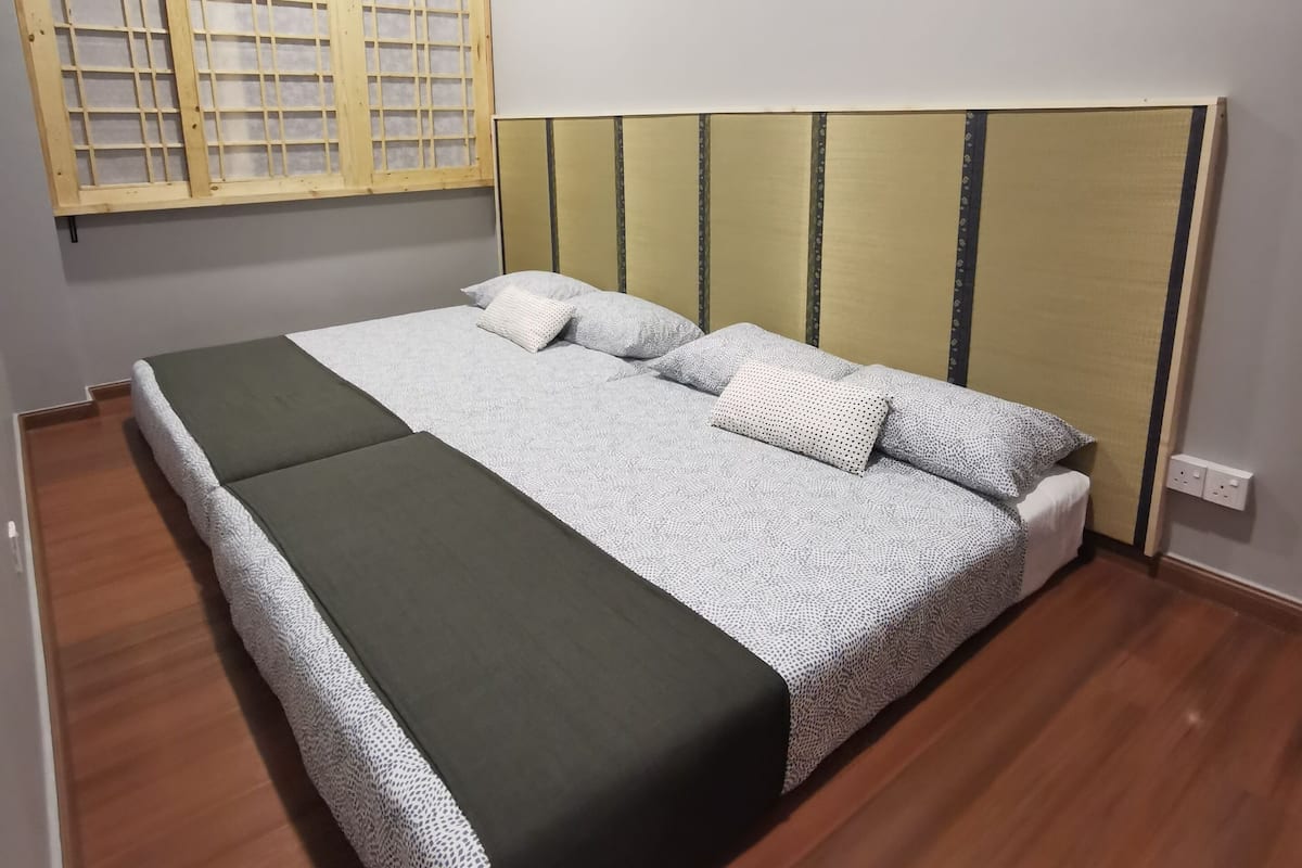 Een slaapkamer met een bed, een raam met houten kader, en een airconditioning aan de muur.