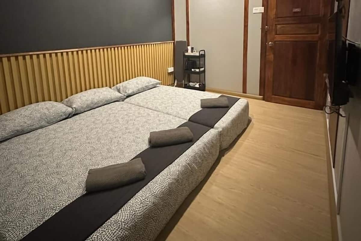 Een slaapkamer met een groot bed, een houten garderobe en een klein tafeltje met een stoel.