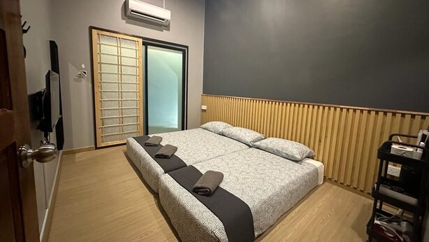 Een hotelkamer met een groot bed, een schuifdeur, een airconditioning en een houten vloer.