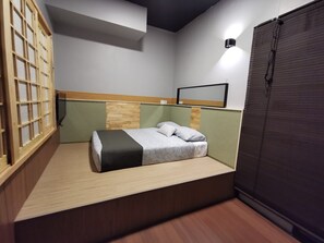 A compact room with a bed, a wooden headboard, a wall-mounted light, and a window with blinds. - Tatami D'Tepi Laut Pangkor (Pangkor Island)