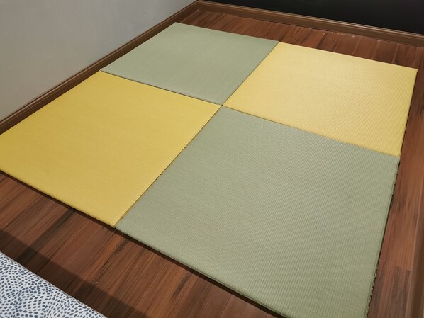 A room with a wooden floor and a large, square, multi-colored mat in the center.