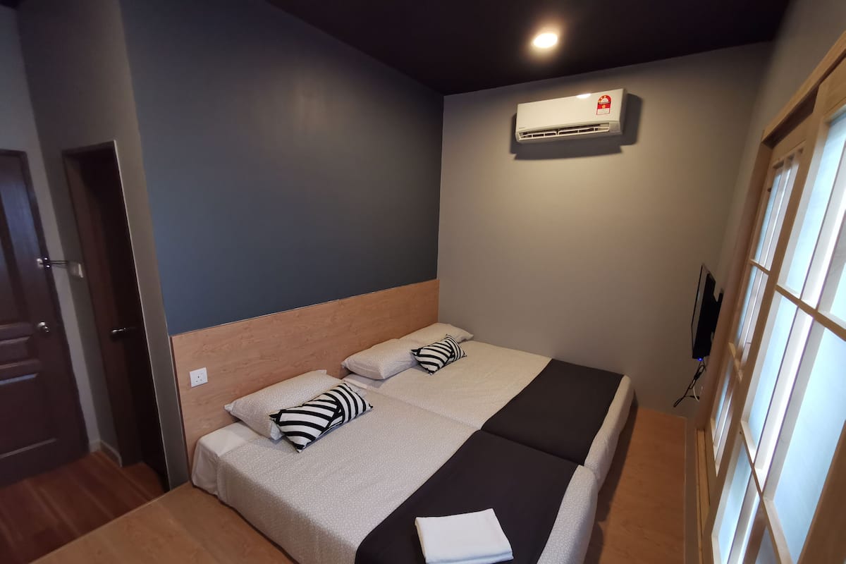 Een slaapkamer met een bed, kussens, een deken, een airconditioning en een televisie.