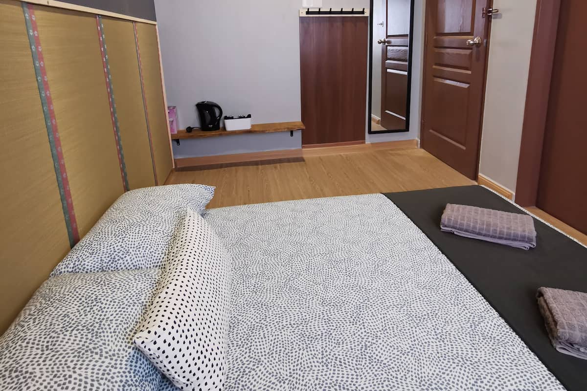 Een slaapkamer met een bed, een houten bankje, een kledingkast en een deur.