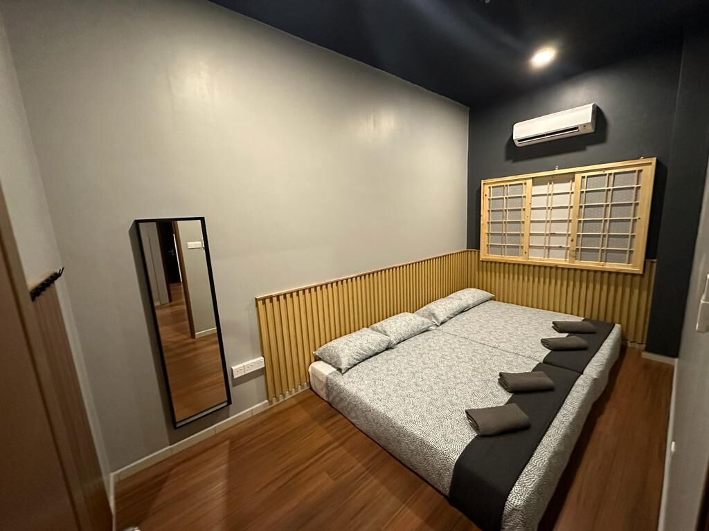 A bedroom with a large bed, a wooden headboard, a mirror, and a window with a grid pattern.