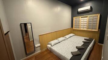 A bedroom with a large bed, a wooden headboard, a mirror, and a window with a grid pattern.