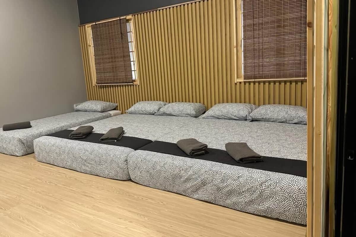 Een kamer met een modern ontwerp, met een groot bed met een gestreept hoofdeinde, een kleiner bed en een zithoek met kussens.