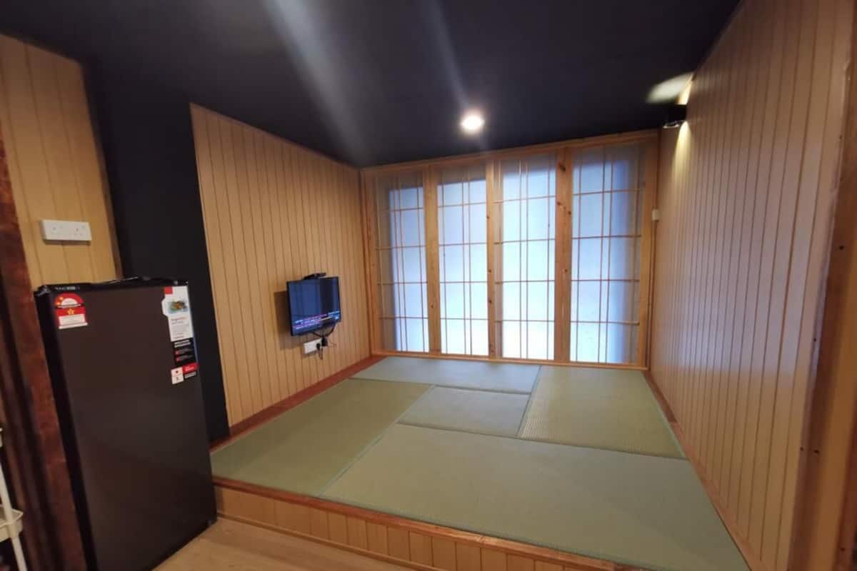 Een kamer met tatami vloerbedekking, een televisie en een koelkast.