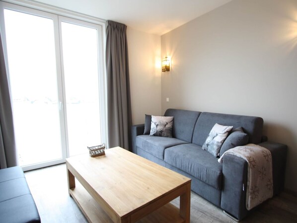 Relax in this stylish living room with a sofa, coffee table, and sliding glass door leading to an outdoor area.