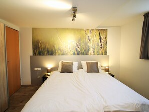Relax in a spacious room with a large bed, wall-mounted light fixture, and a nightstand with a lamp.