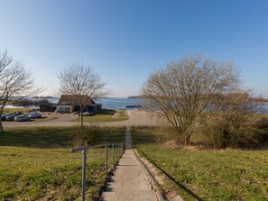 A pathway leading to a beach with a building in the background. - Holiday Home Near Veerse Meer Lake Wolphaartsdijk (Wolphaartsdijk)