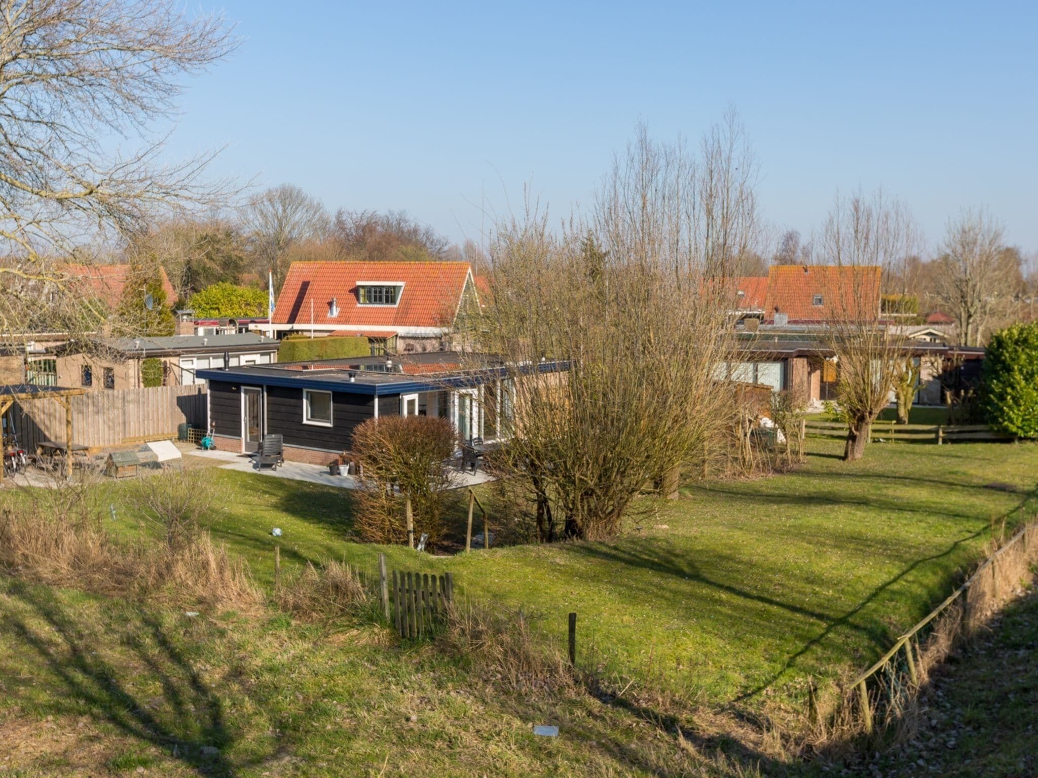 A residential area with houses, a grassy yard, and a wooden fence.