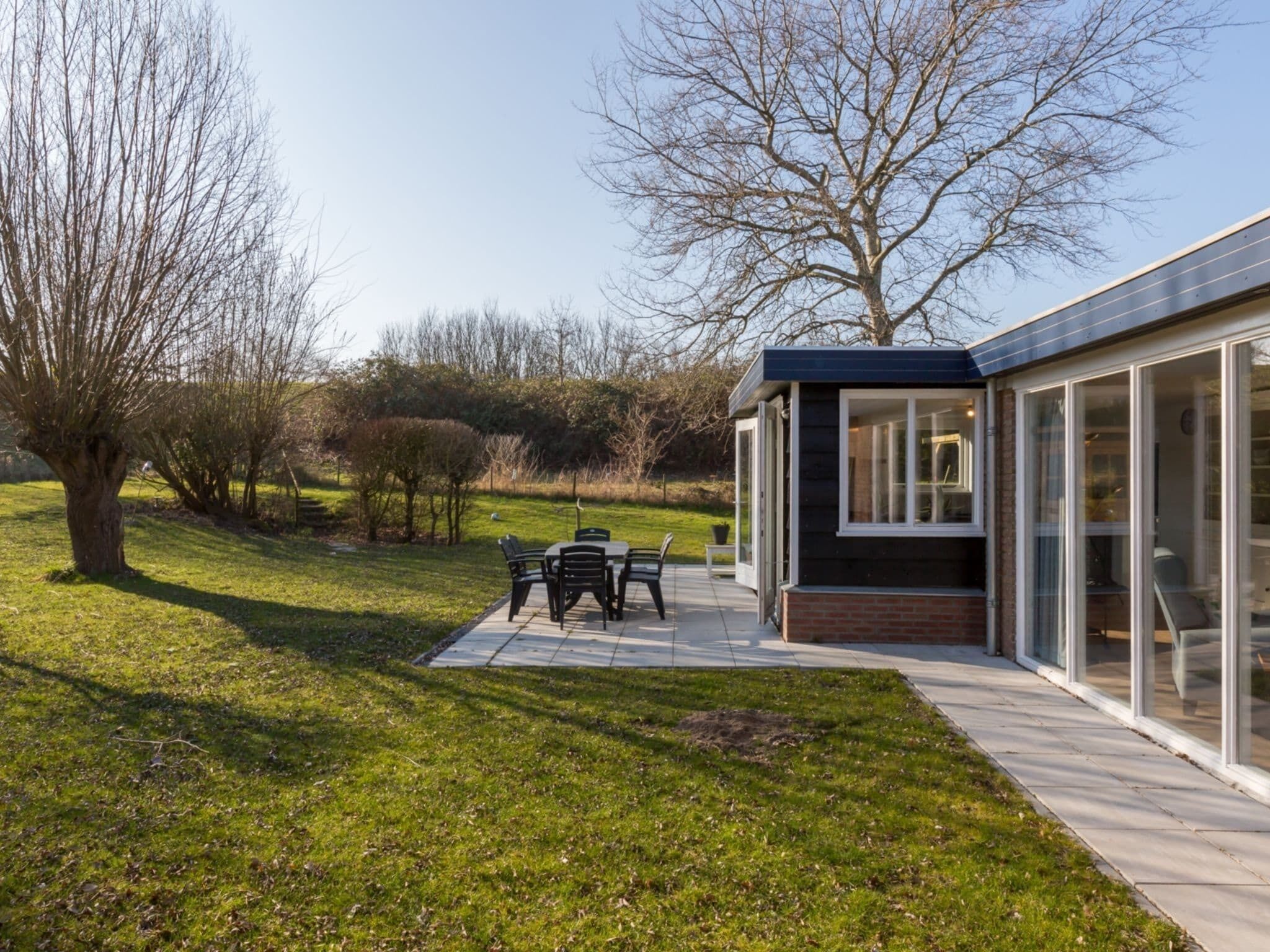 A modern house with a patio, a dining table, and chairs.
