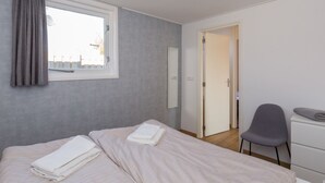 A bedroom with a bed, a chair, a desk, and a window with curtains. - Holiday Home Near Veerse Meer Lake Wolphaartsdijk (Wolphaartsdijk)