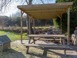 A wooden picnic shelter with benches, surrounded by a garden and a bicycle rack. - Holiday Home Near Veerse Meer Lake Wolphaartsdijk (Wolphaartsdijk)