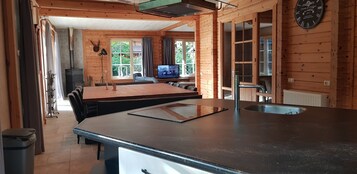 A wooden cabin interior with a kitchen area featuring a black countertop, a sink, and a dining table with chairs.