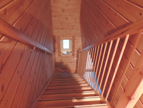 Un interior de madera con una escalera que lleva a una pequeña ventana.