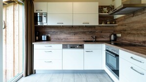 Una cocina moderna con gabinetes blancos, un protector contra salpicaduras de madera y electrodomésticos de acero inoxidable.