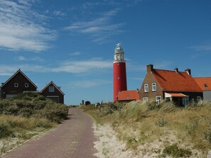 A coastal path leading to a red lighthouse and traditional houses with red roofs. - Mansion in De Cocksdorp (De Cocksdorp)