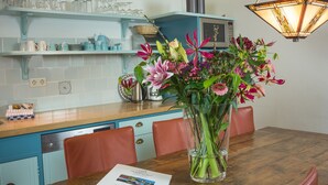A dining area with a wooden table, chairs, a vase of flowers, and a menu on the table. - Mansion in De Cocksdorp (De Cocksdorp)
