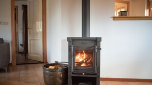 A modern living room with a wood-burning stove, a large metal pot, and a sofa. - Mansion in De Cocksdorp (De Cocksdorp)