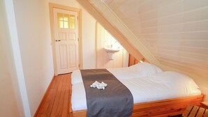 A bedroom with a wooden bed, a grey blanket, and a white door with glass panels. - Mansion in De Cocksdorp (De Cocksdorp)